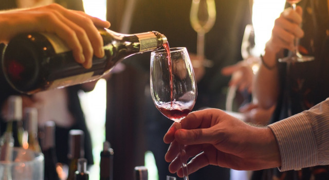 A woman serving a man a glass of whine