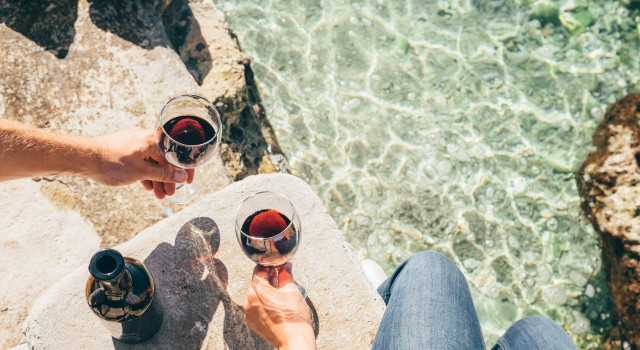 People with wine glasses by water