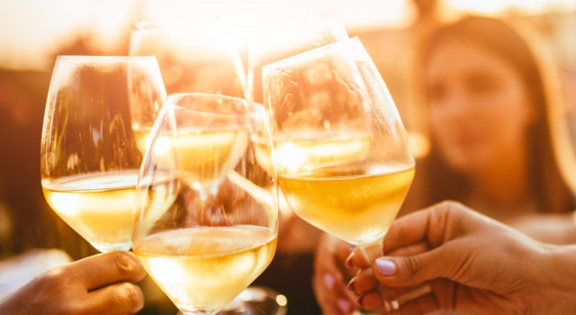 Group of people clinking glasses of white wine.